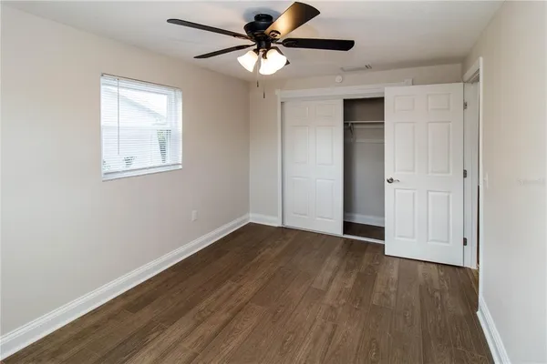 a view of an empty room with window and wooden floor