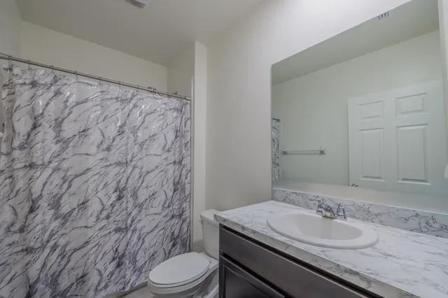 a bathroom with a granite countertop sink toilet and shower