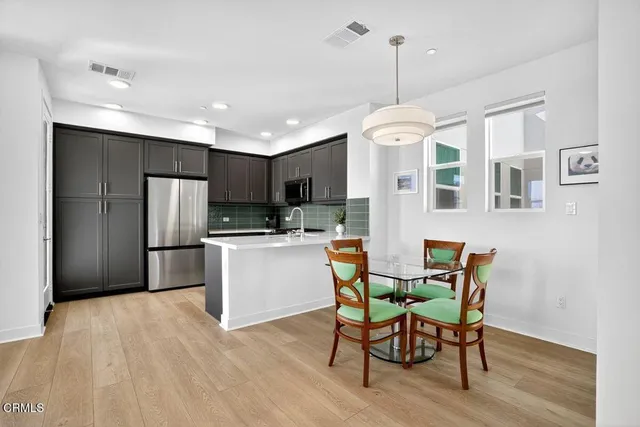 a kitchen with stainless steel appliances granite countertop a refrigerator a stove top oven a dining table and chairs