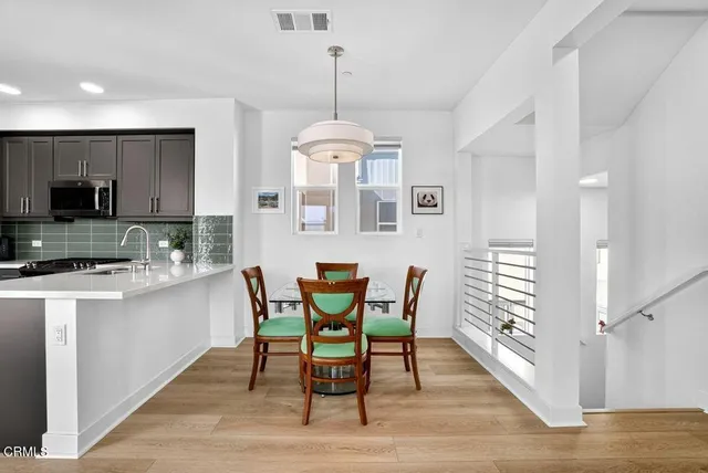 a kitchen with stainless steel appliances granite countertop a dining table chairs a sink and dishwasher a refrigerator with wooden floor