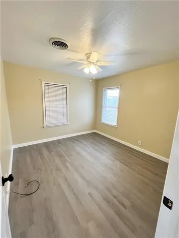 a view of empty room with wooden floor and fan
