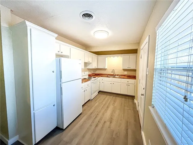 a kitchen with a refrigerator a sink and dishwasher with wooden floor