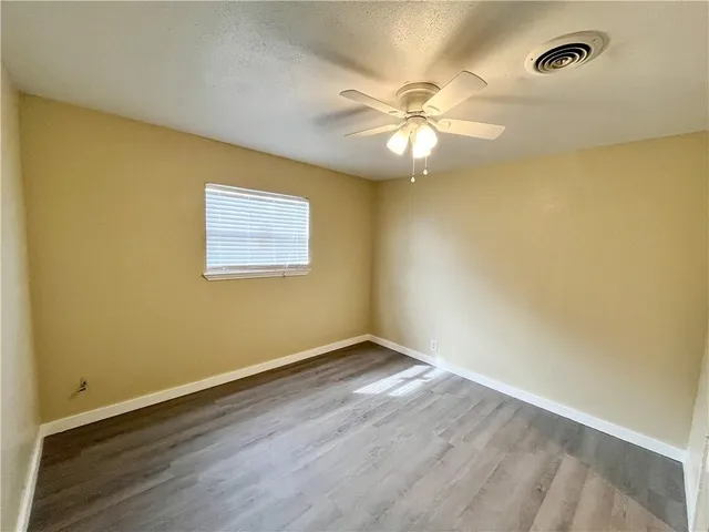 an empty room with a window and ceiling fan