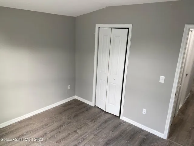 an empty room with wooden floor and mirror