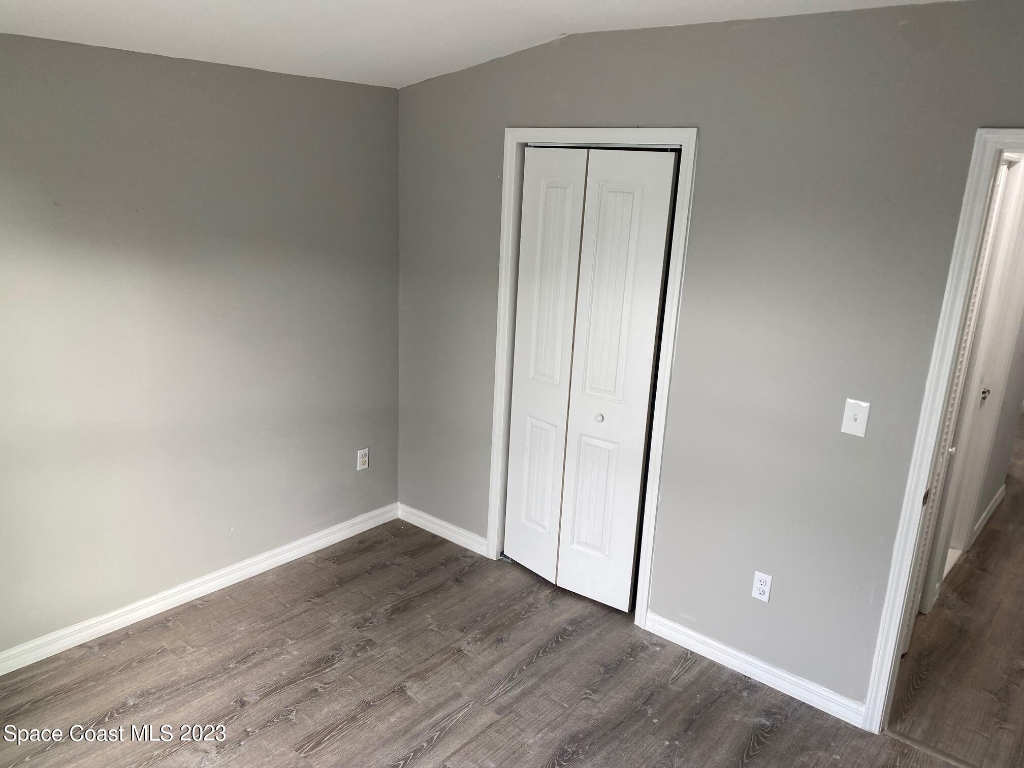2944 Century Oaks Circle Malabar, FL 32950 - Photo 12 of 16 an empty room with wooden floor and mirror