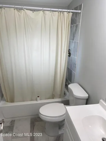 a white toilet sitting next to a shower