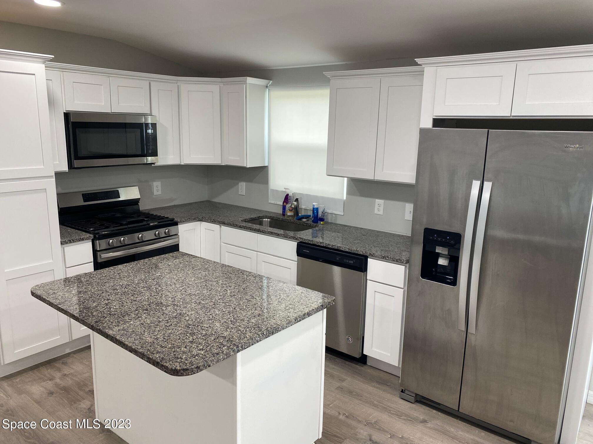 2944 Century Oaks Circle Malabar, FL 32950 - Photo 2 of 16 a kitchen with a center island and stainless steel appliances