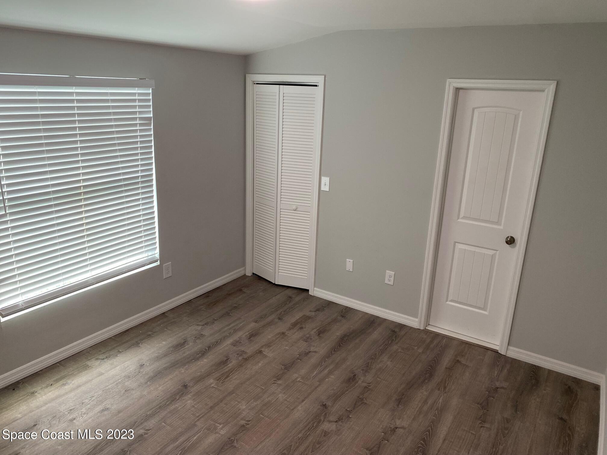 2944 Century Oaks Circle Malabar, FL 32950 - Photo 6 of 16 a view of an empty room with wooden floor and a window