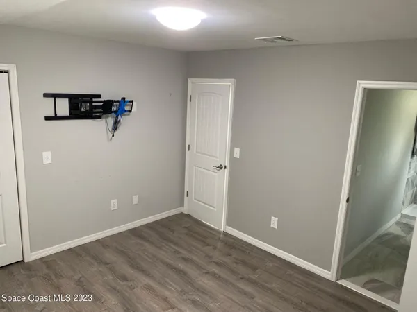 an empty room with wooden floor and a ceiling fan