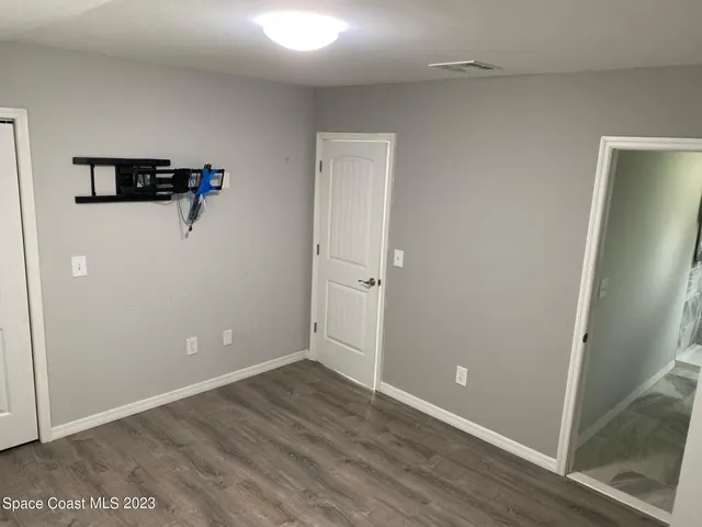 an empty room with wooden floor and a ceiling fan