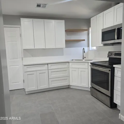 a kitchen with white cabinets and stainless steel appliances