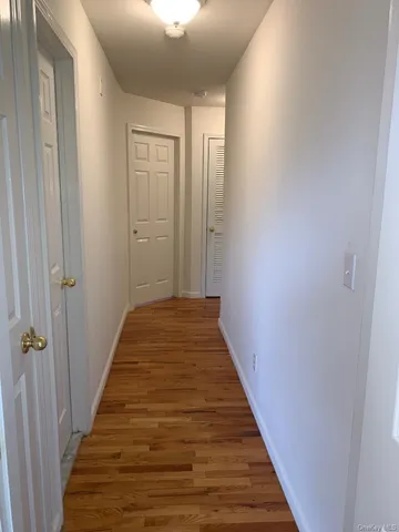 a view of a hallway with wooden floor and closet