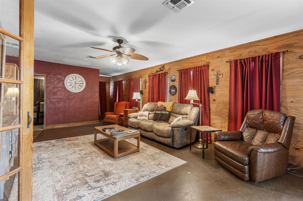 13315 Highway 281 Scotland, TX 76379 - Photo 13 of 40 Living/den area featuring wood-paneled walls and a textured accent wall leading to the safe room
