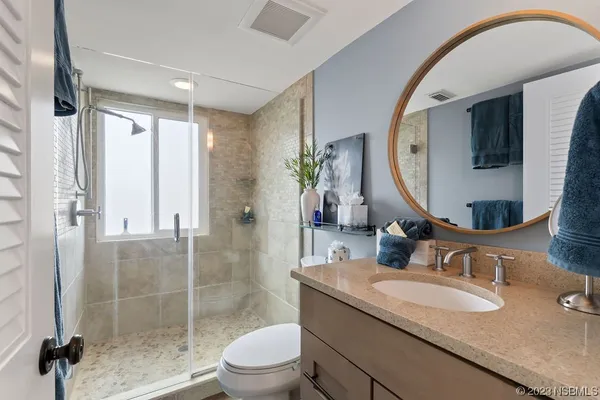 a bathroom with a granite countertop sink a mirror and a shower