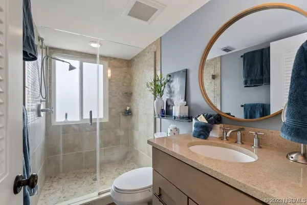 a bathroom with a granite countertop sink a mirror a glass door a shower and vanity