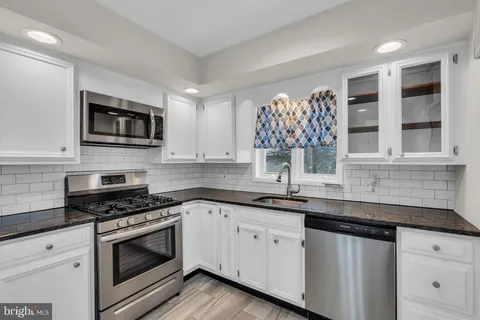a kitchen with granite countertop white cabinets stainless steel appliances and a sink