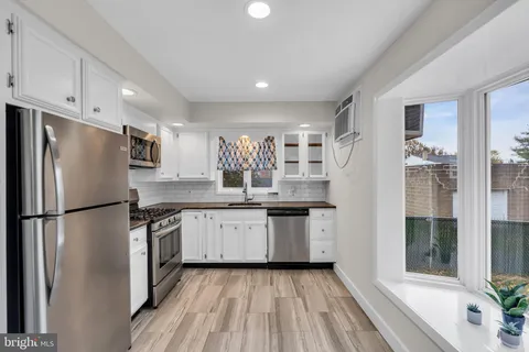 a kitchen with granite countertop a refrigerator a sink a stove and white cabinets