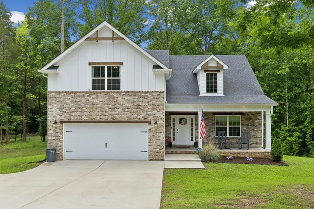 a front view of a house with a garden and trees