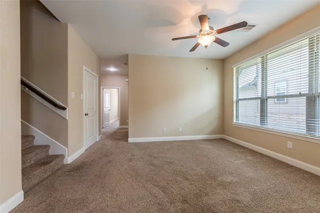 an empty room with chandelier fan and windows