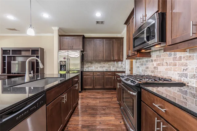 a kitchen with granite countertop a table chairs microwave and cabinets
