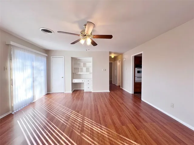 a view of empty room with wooden floor and fan