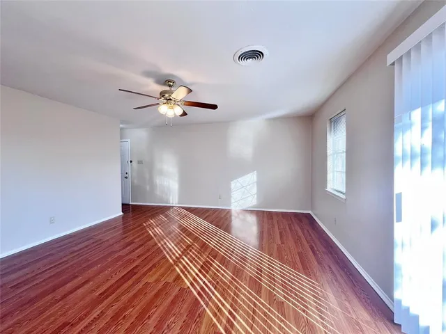 a view of an empty room with wooden floor and a window