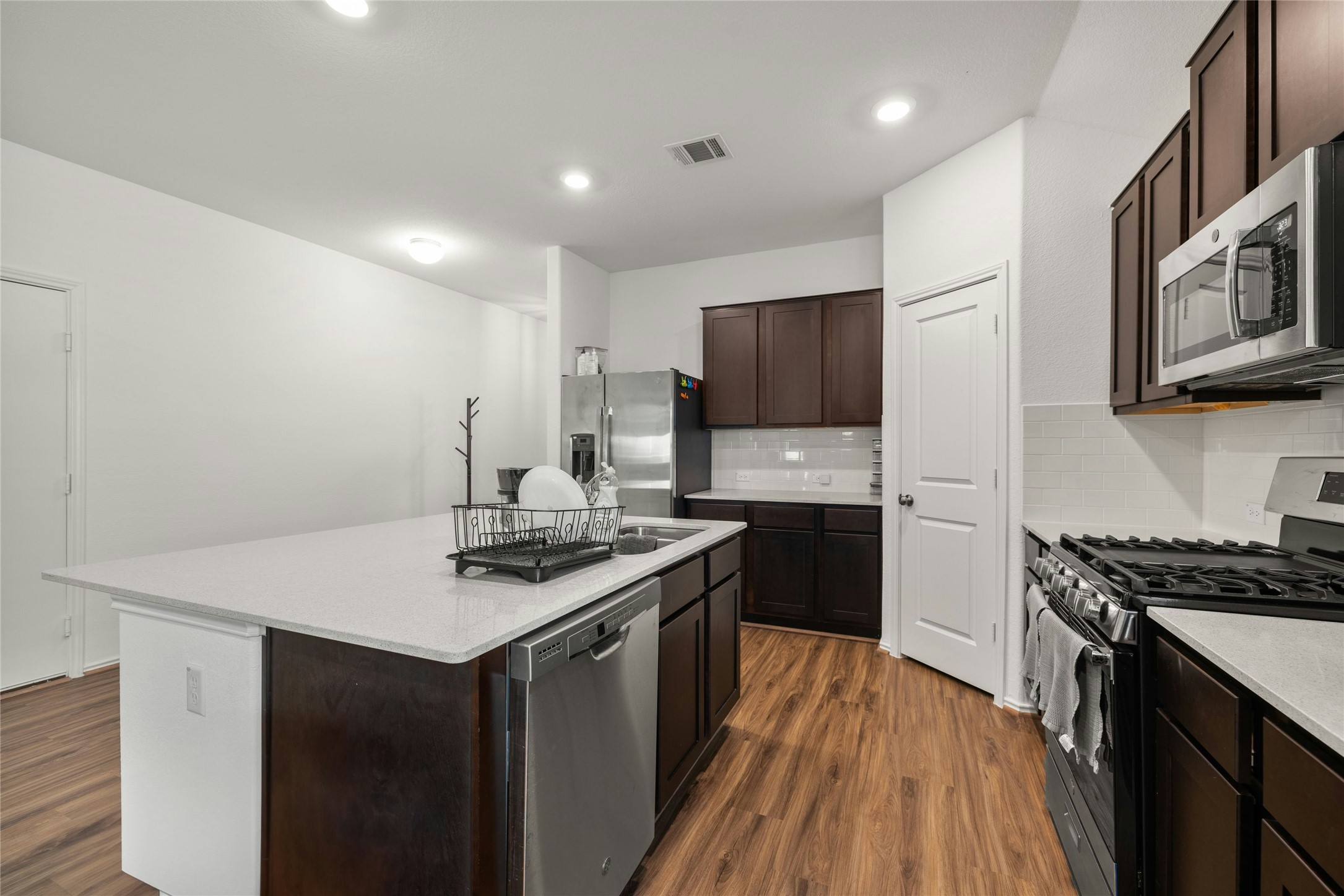 11813 Roscommon Trail Austin, TX 78754 - Photo 8 of 28 a kitchen with stainless steel appliances a sink dishwasher stove refrigerator and cabinets with wooden floor