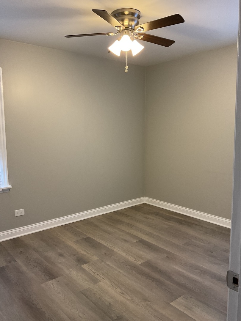 17031 Trapet Avenue Hazel Crest, IL 60429 - Photo 5 of 13 en empty room with wooden floor and fan