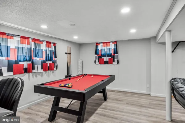 a living room with furniture pool table and paintings on the wall