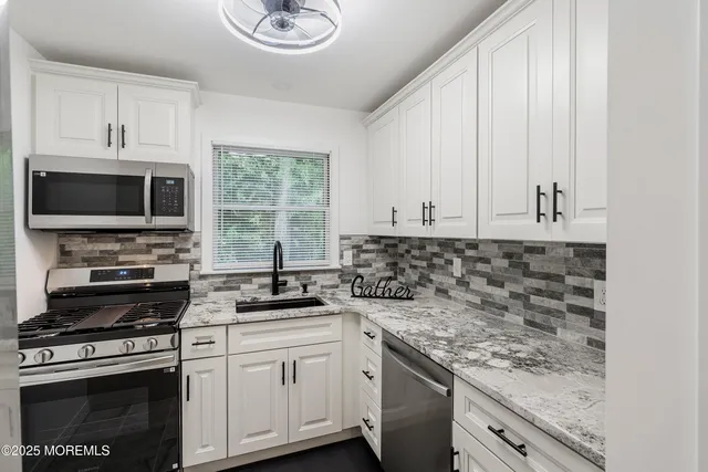 a kitchen with granite countertop a sink a stove and microwave