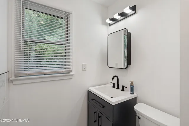 a bathroom with a toilet a sink a mirror and a window