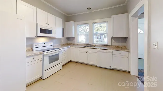 a kitchen with white cabinets appliances a sink and a window