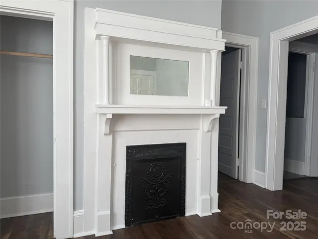 a view of an empty room with wooden floor and a fireplace