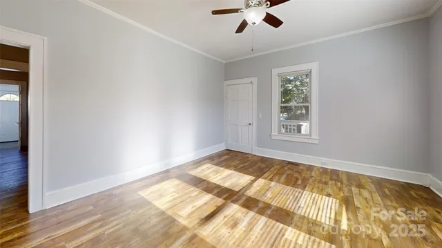 a view of empty room with wooden floor and fan