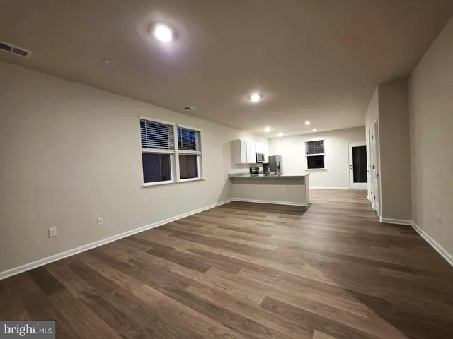 a view of a kitchen with an empty room and wooden floor