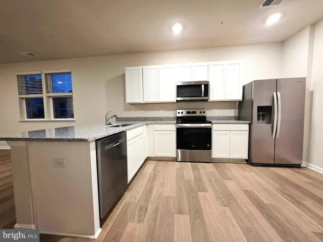 a kitchen with stainless steel appliances granite countertop a stove top oven a sink and a refrigerator