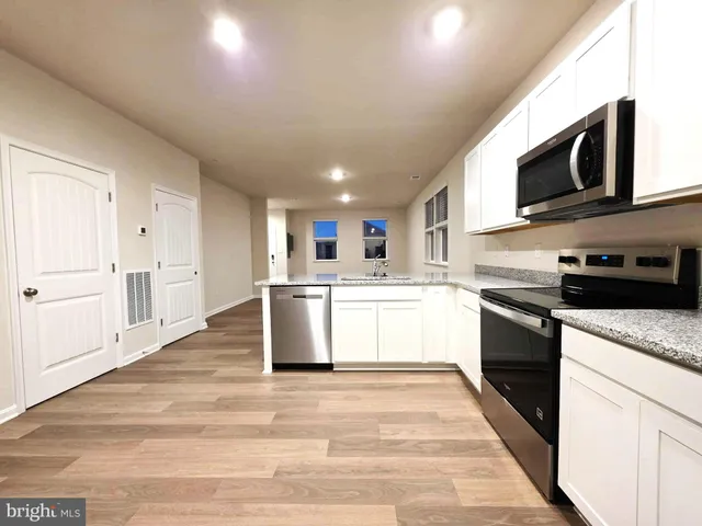 a large kitchen with stainless steel appliances granite countertop a stove a sink dishwasher and a refrigerator with wooden floor