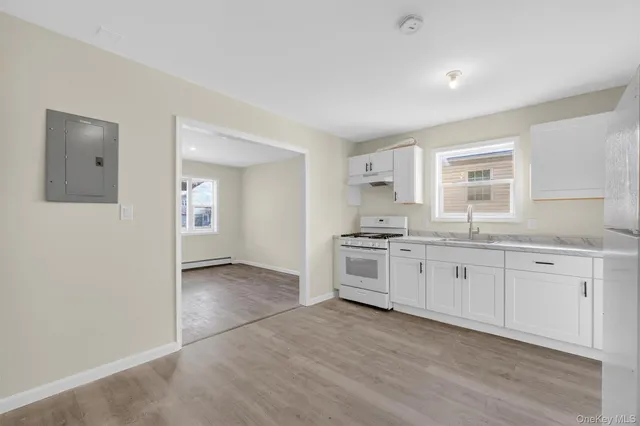 a large white kitchen with granite countertop a stove a sink and white cabinets