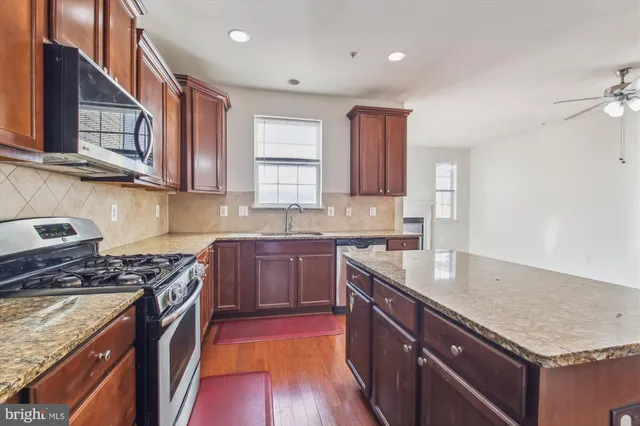 a kitchen with stainless steel appliances granite countertop a sink stove and cabinets