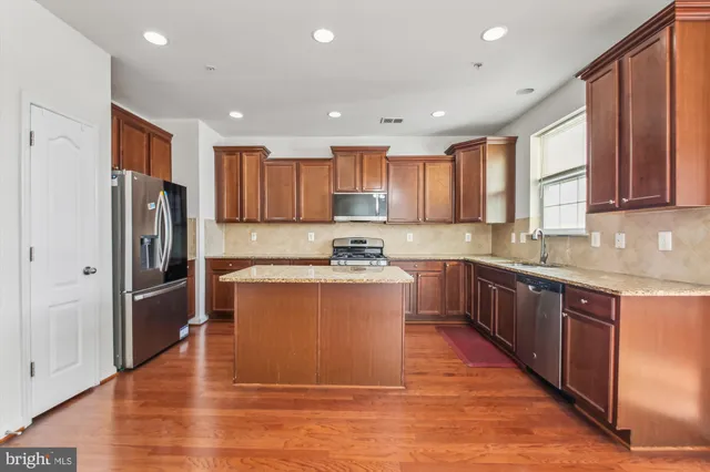 a large kitchen with stainless steel appliances granite countertop a refrigerator a sink dishwasher a stove and oven with wooden floor