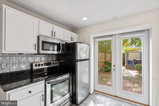 a kitchen with granite countertop a refrigerator stove and microwave