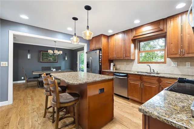 a kitchen with granite countertop kitchen island stainless steel appliances a sink stove and table