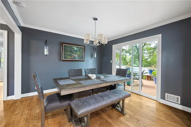 a dining room with wooden floor a chandelier a wooden table and chairs