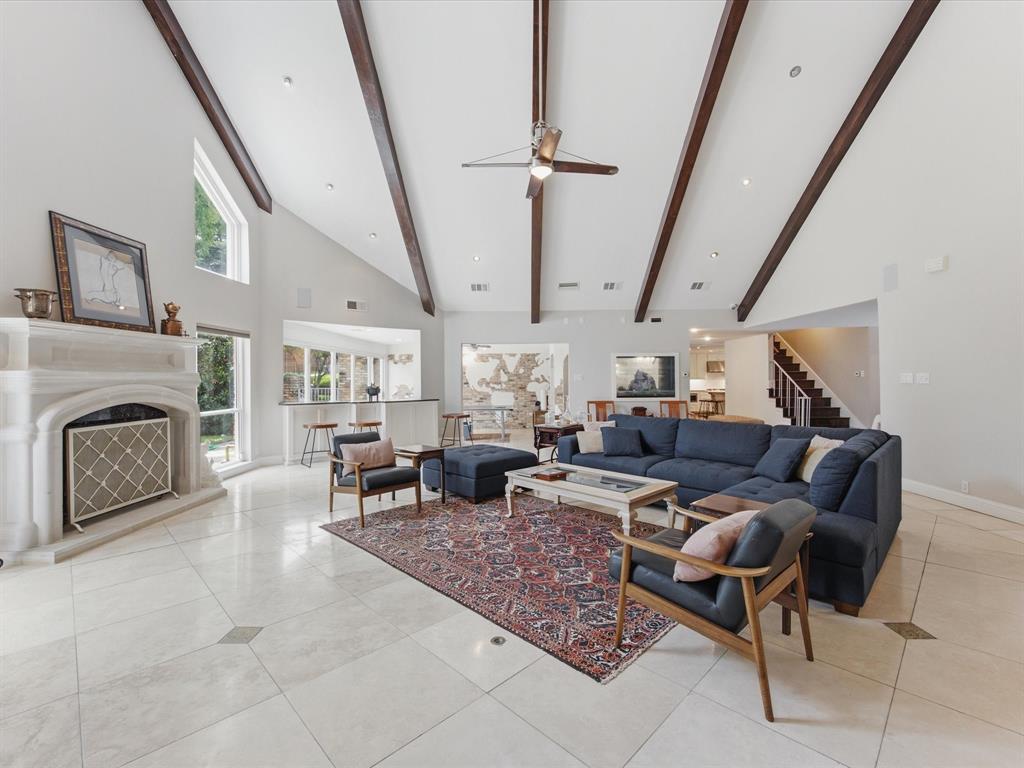 6160 Spring Valley Road Dallas, TX 75240 - Photo 16 of 40 Vaulted ceiling with exposed wood beams, a stone fireplace, and light-tone tile flooring
