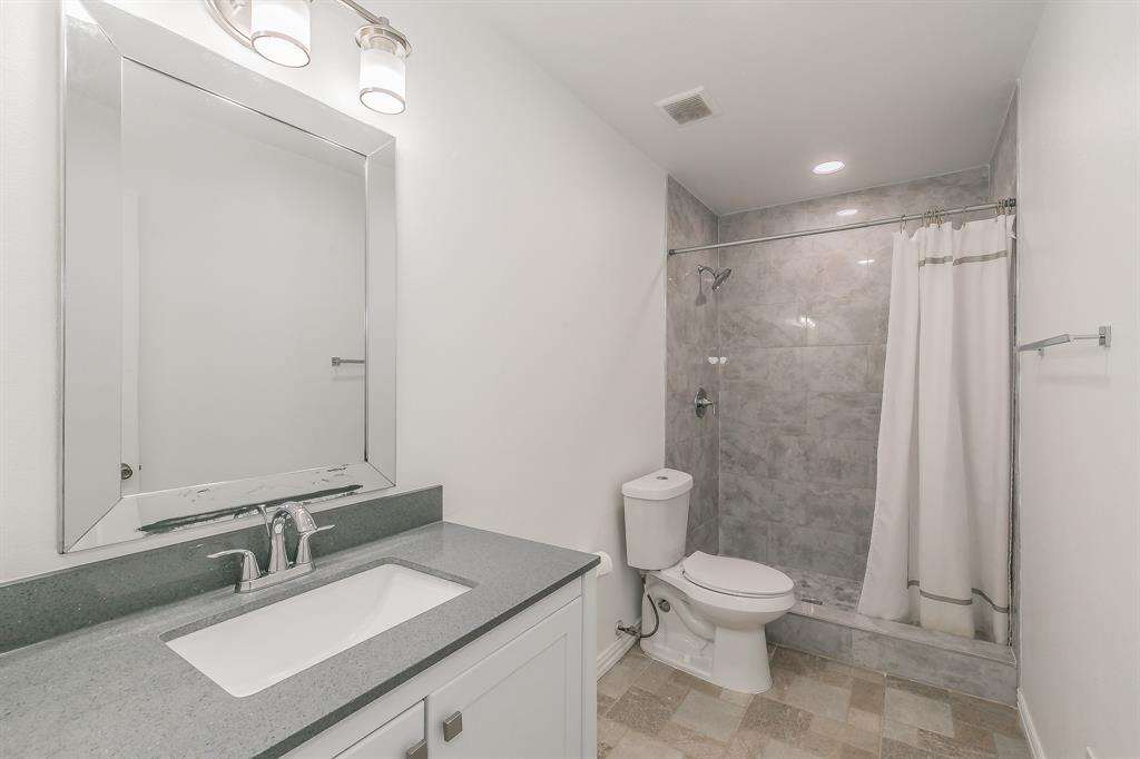 904 Sherman Street Tioga, TX 76271 - Photo 28 of 40 a bathroom with a granite countertop sink toilet a mirror and shower