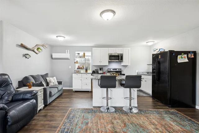 a living room with furniture a flat screen tv and kitchen view