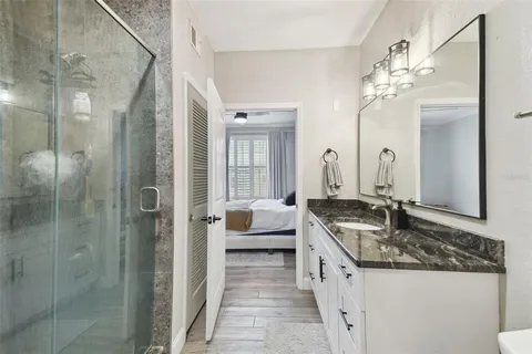 a spacious bathroom with a granite countertop sink a mirror and shower