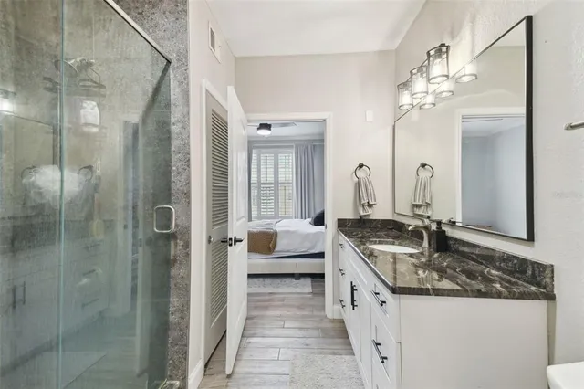 a spacious bathroom with a granite countertop sink a mirror and shower