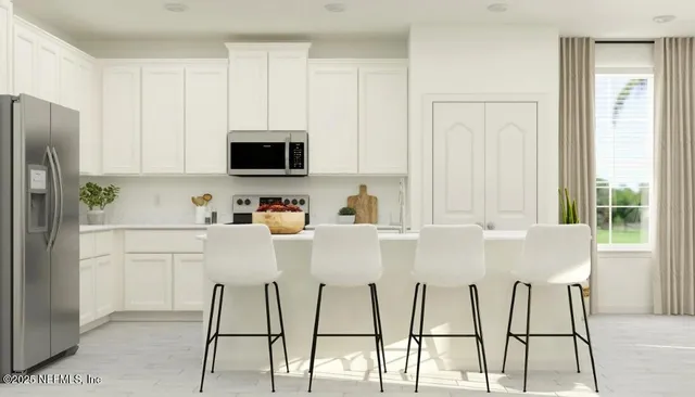 a white kitchen with a dining table chairs and a refrigerator