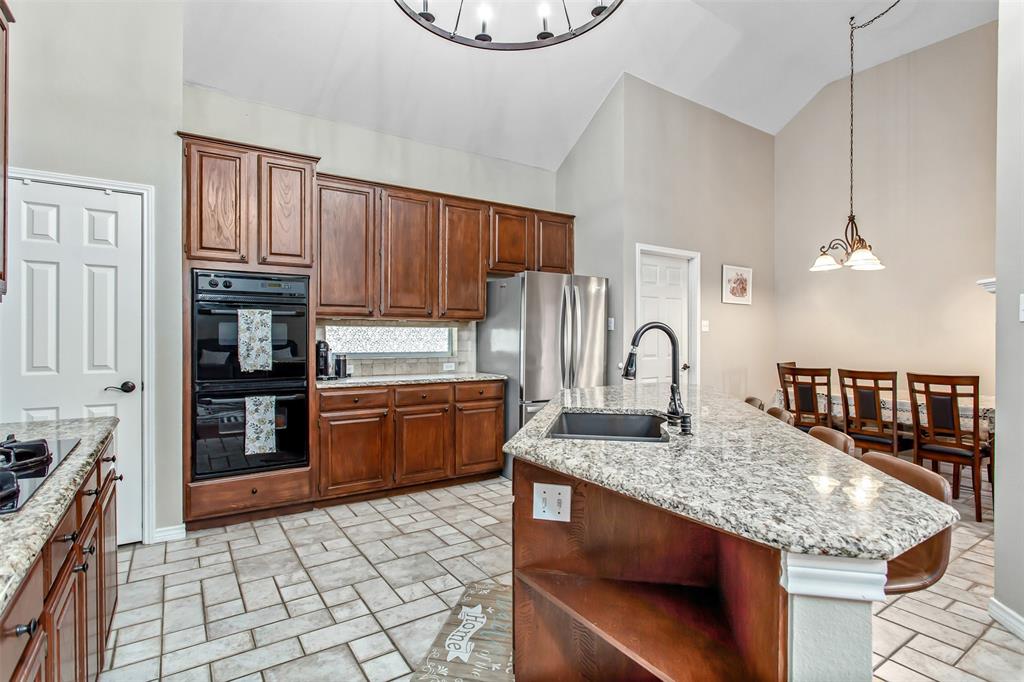 5916 Mossbrook Trail Dallas, TX 75252 - Photo 16 of 40 a kitchen with granite countertop a stove a refrigerator and wooden cabinets